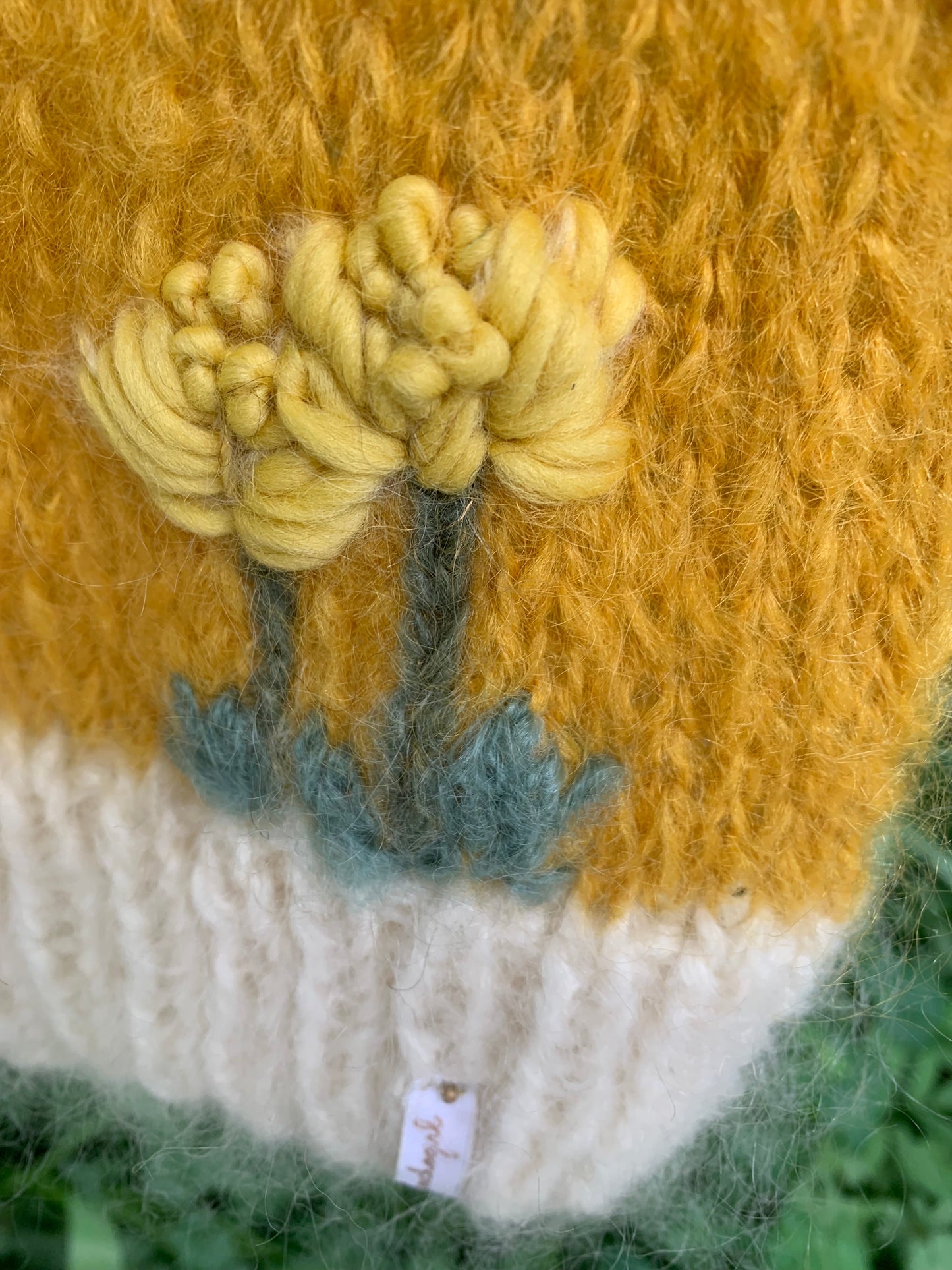 To broderte løvetenner på en gul strikkevest