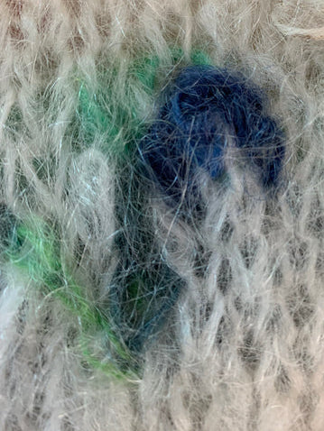 Brodert og strikket blåklokke på hvit genser