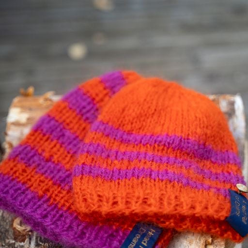 Håndstrikket ribbelue i oransje og rosa striper med heng bak – Bohemian Pink fra CosyMonday